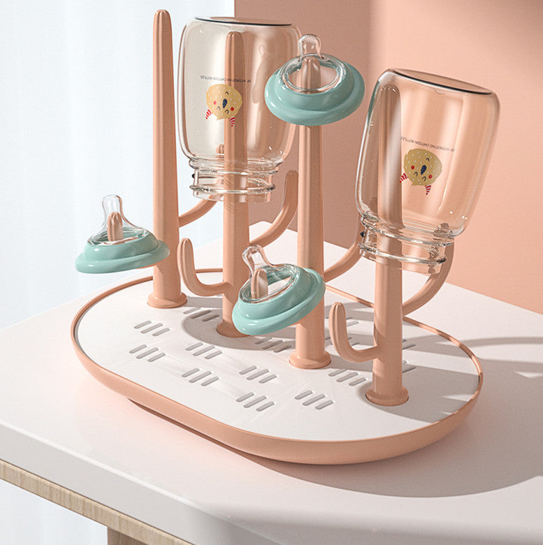 Pink and white baby bottle drying rack with bottles on a white surface.