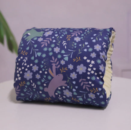 Arm pillow with floral pattern and bunnies on dark blue with a light background