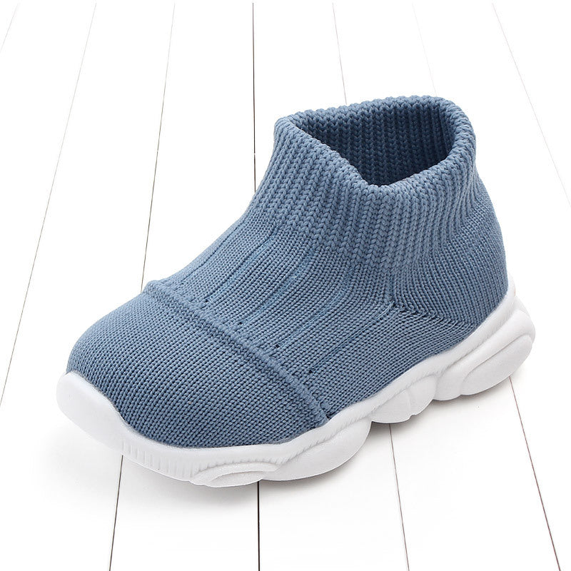 Blue baby shoe with white sole on a light wooden floor