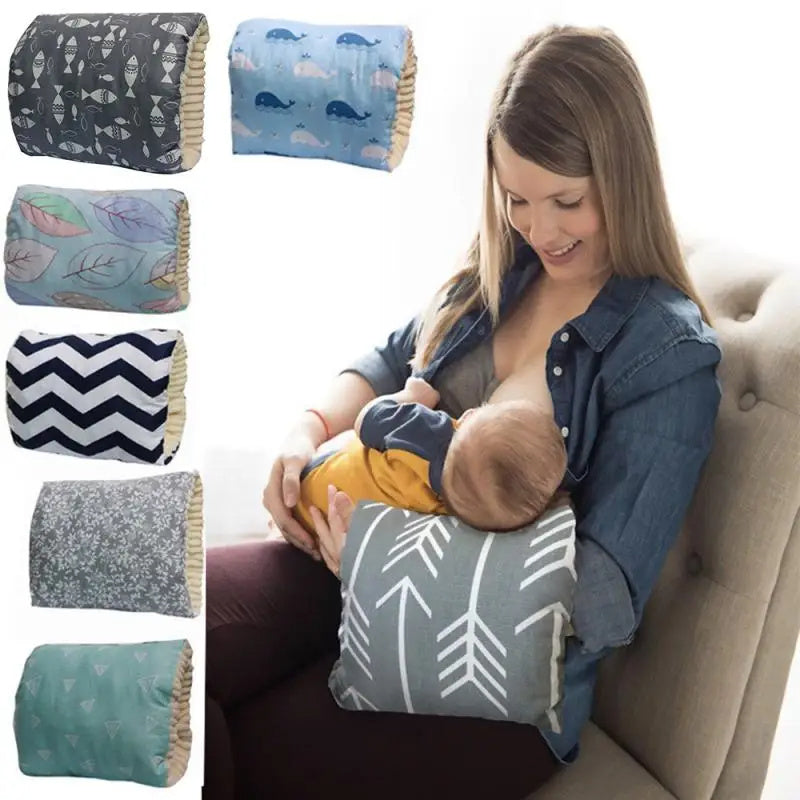 Woman breastfeeding a baby while sitting on a couch, with various patterned pillows displayed.
