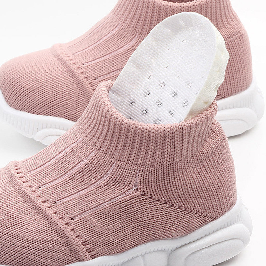 Pink baby shoes with white soles on a white background