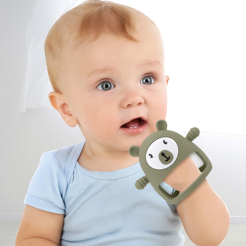 Baby holding bear-shaped green teether on a white background