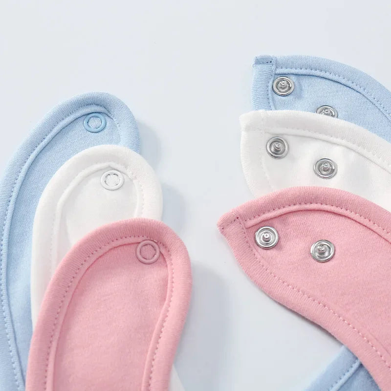 Set of pastel-colored baby bibs with buttons on a light background
