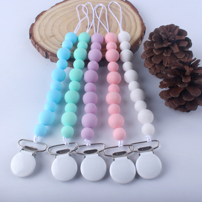 Silicone pacifier clips in various colors on a wooden block 