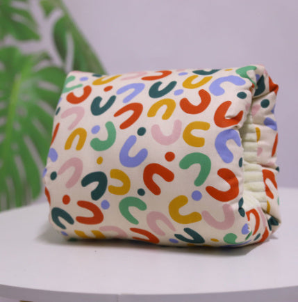 Arm pillow with U pattern on beige with a plant in the light background 