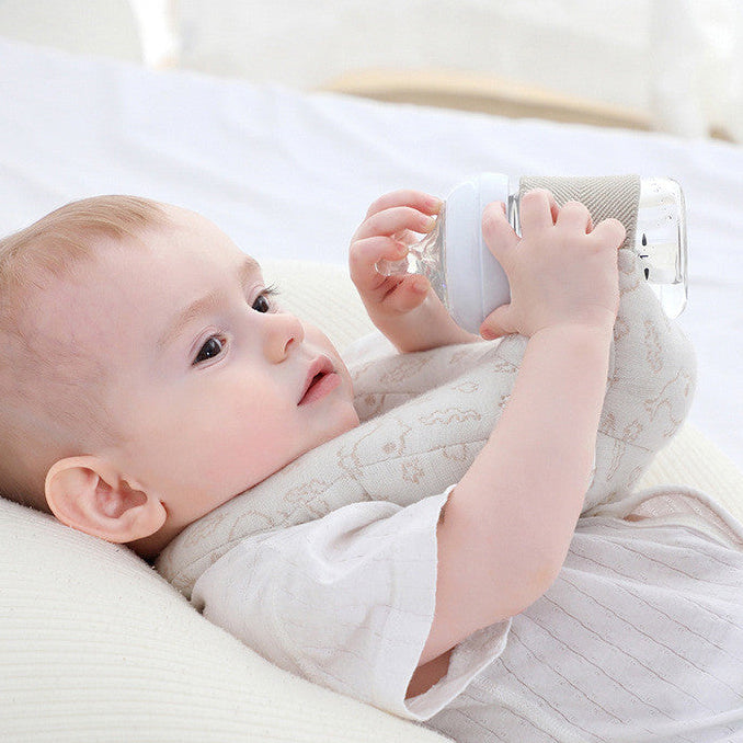 Baby lying on a white pillow holding a white toy